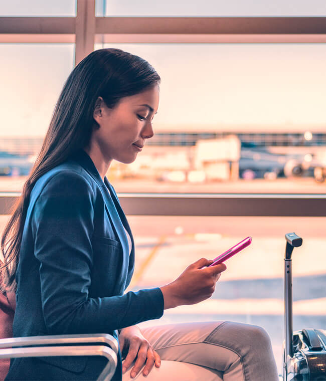 Woman sitting in airport terminal looking at smartphone