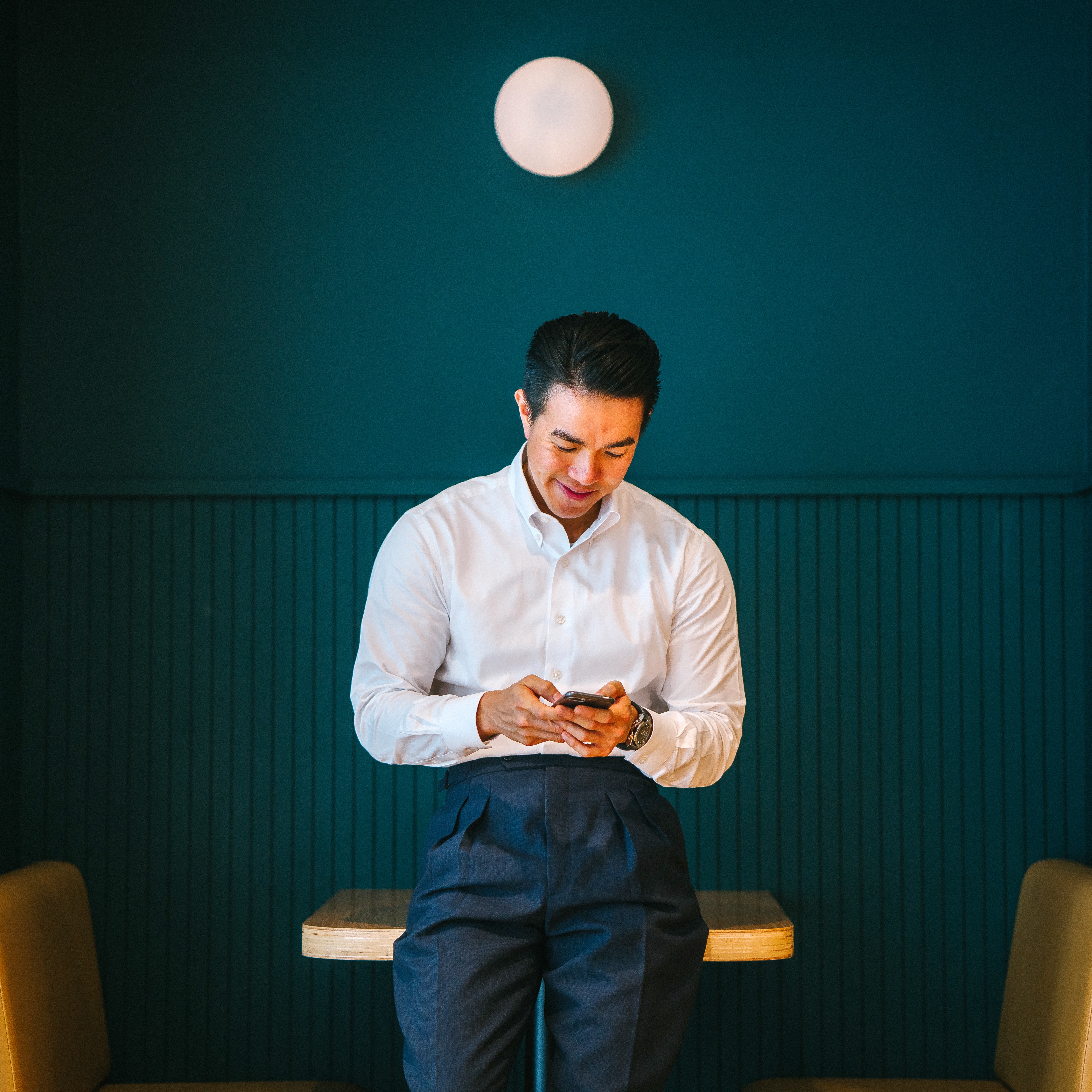 Asian businessman leaning on restaurant table looking at smartphone