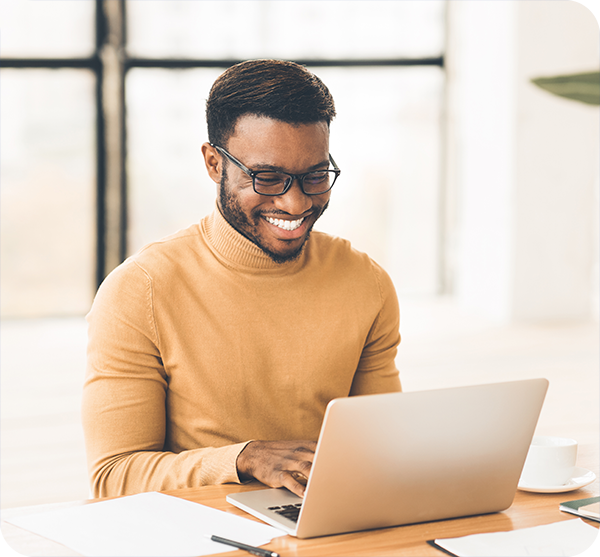 Smiling African American man in glasses looking at laptop